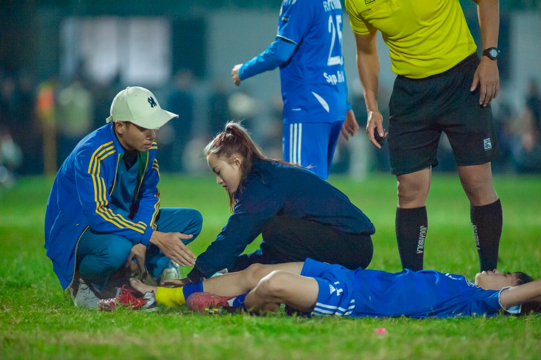 Fisioterapeuta atendiendo a un jugador lesionado en una cancha de pasto