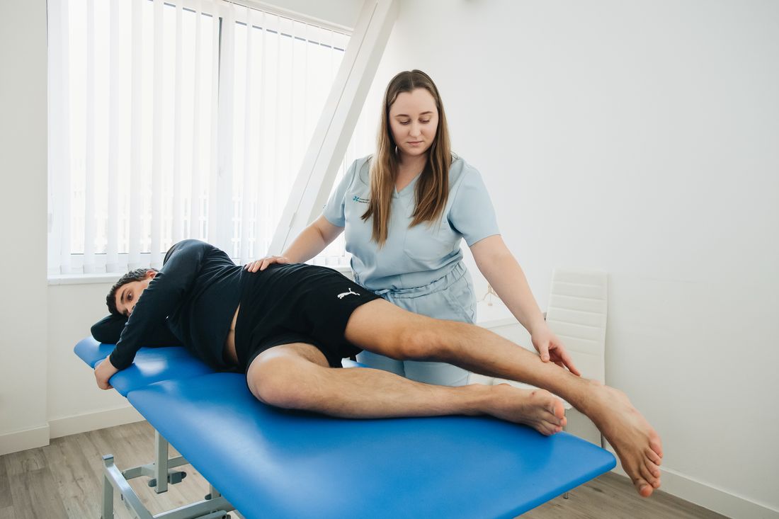 Paciente haciendo ejercicio de rehabilitación guiado por una fisioterapeuta sobre un tapete azul